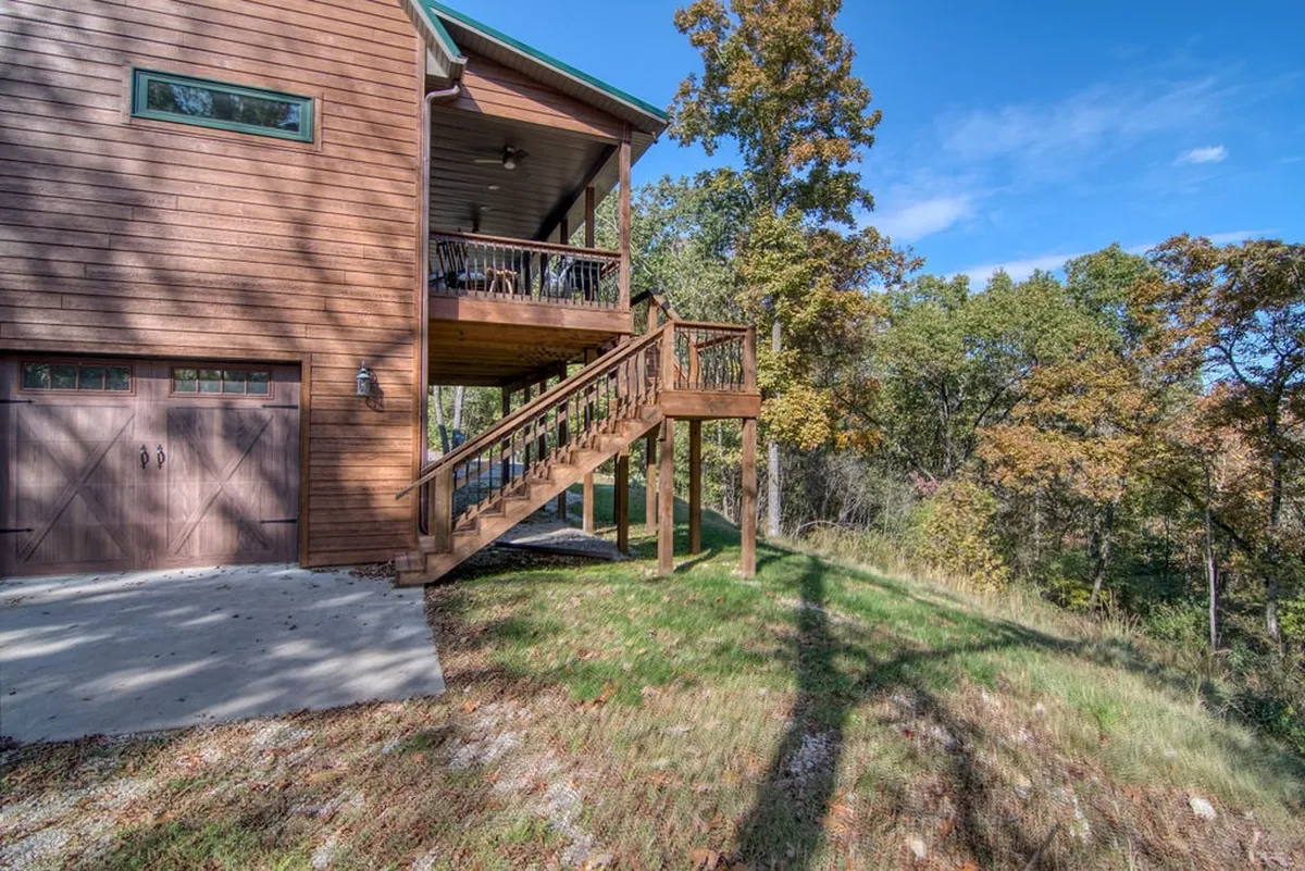 A peaceful wooden deck with stairs leading to a welcoming entrance, set amidst tall trees. The deck offers a serene vantage point to appreciate the surrounding nature, ideal for morning coffee or evening stargazing.