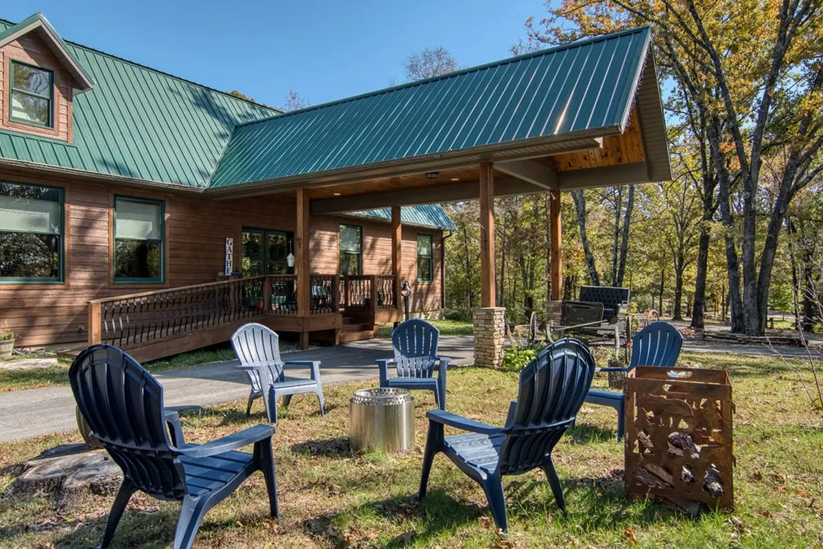 A cozy wooden cabin with a fire pit and comfortable outdoor seating area, surrounded by mature trees. The scene is set for quiet evenings or intimate gatherings under the stars.