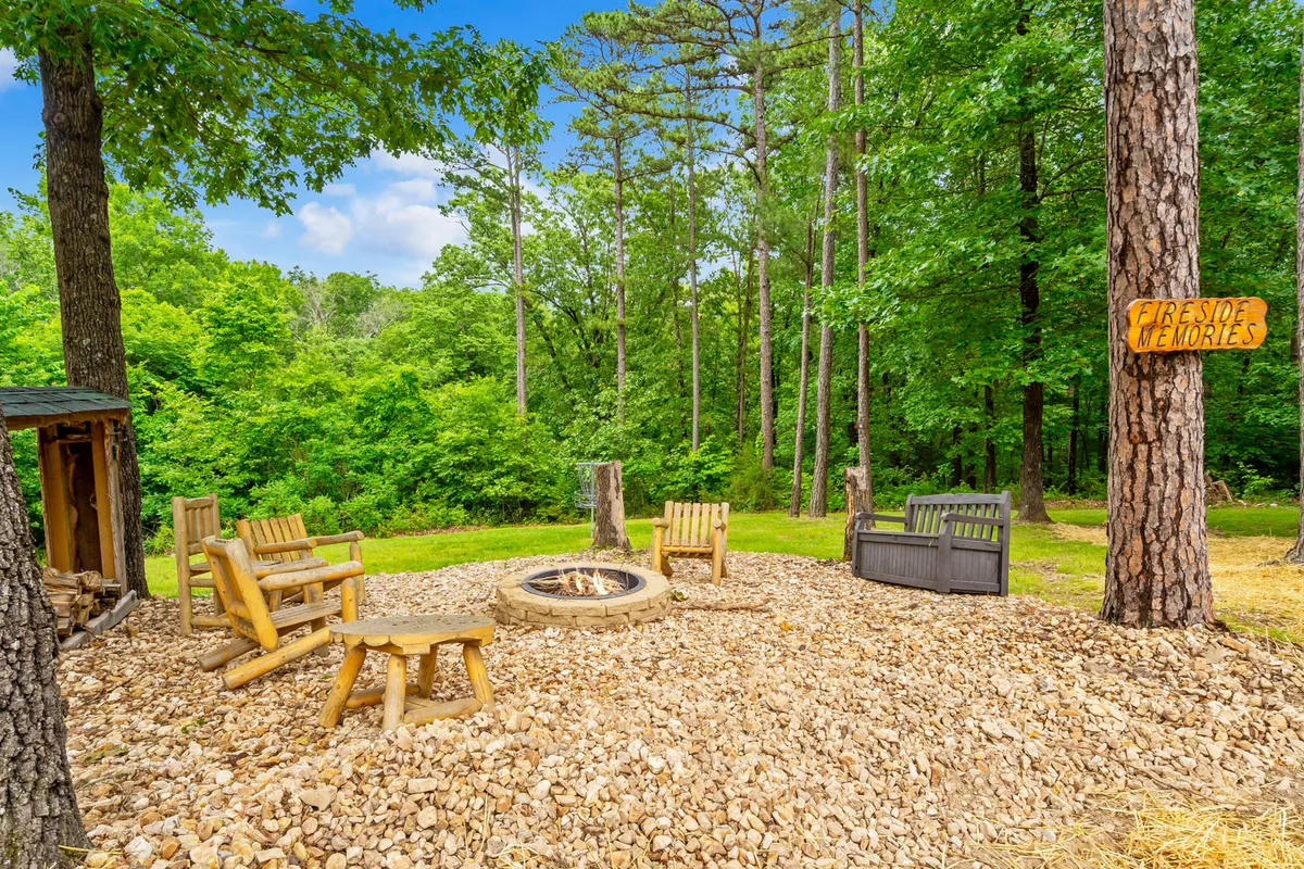 A cozy fire pit area features wooden seating, a sign reading 'Fireside Memories,' and is surrounded by tranquil trees. The inviting setup suggests evenings spent sharing stories, stargazing, and building lasting family bonds.