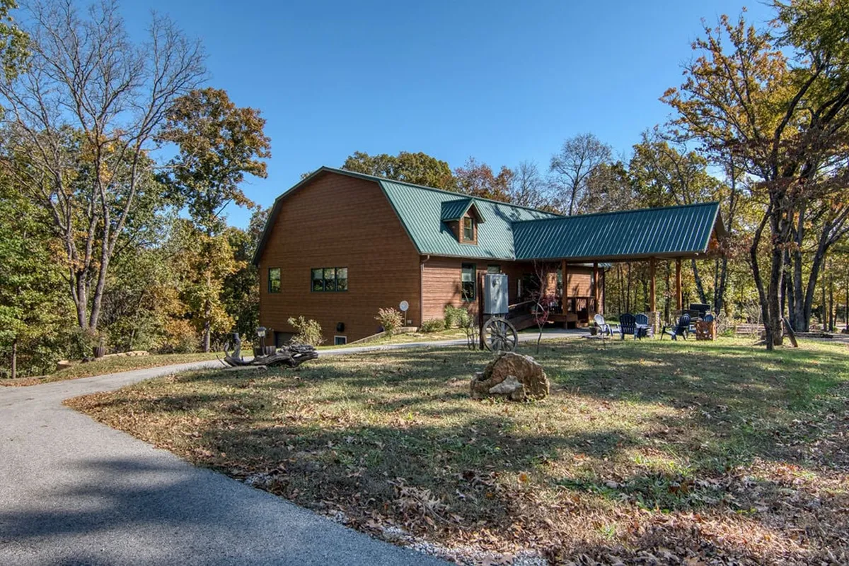The exterior of the house with a welcoming porch, surrounded by trees and a gravel path. The porch is designed for relaxation, morning coffee, or gathering with friends against the backdrop of nature.